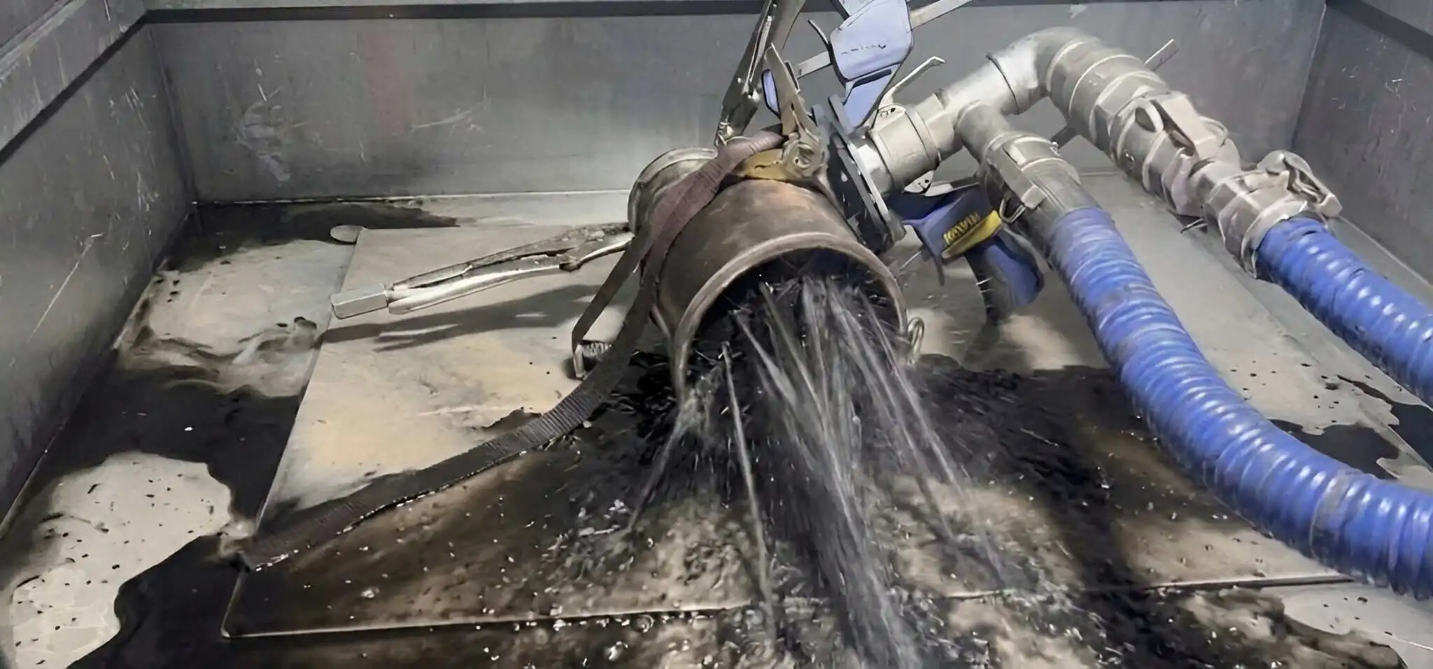 A diesel particulate filter removed from the car and strapped into the wash cabinet, black soot flushing out under water pressure