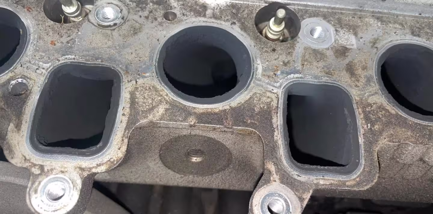 Intake ports on the cylinder head with the manifold off, coated in carbon and grime