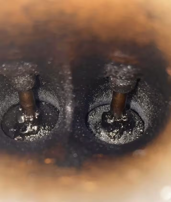 Two intake valves caked in baked-on carbon, before walnut blasting