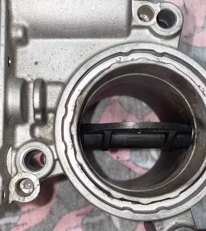 The same throttle body after cleaning by hand, bare metal bore and a clean butterfly plate